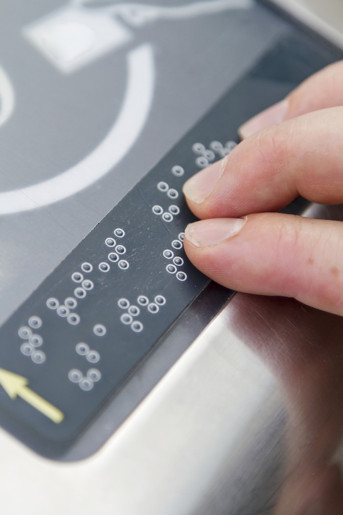 Close up fingers are touching a braille device.